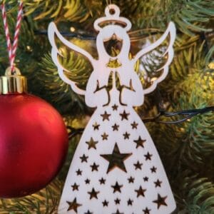 Finished wooden Christmas angel ornament with a starry dress pattern hanging on a Christmas tree next to a red bauble, made from a free SVG laser cut file.