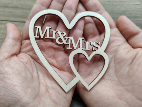 Wooden interlocking hearts wedding sign with Mr and Mrs text cutout held in hands, laser cut file template for Free Cut Crafts.